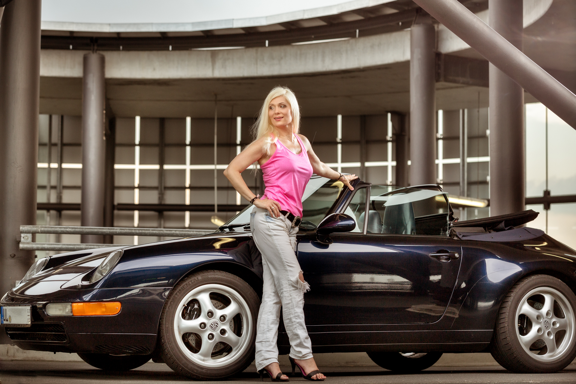 Blonde Frau mit langen Haaren vor einem Porsche Caprio
